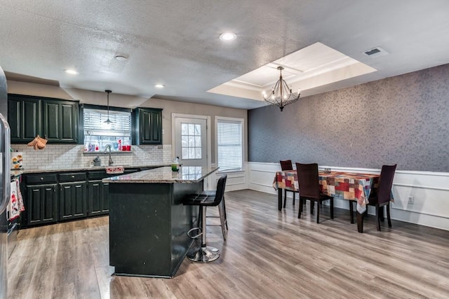 209 E County Line Rd, Royse City, TX 75189 - kitchen featuring light wood-type flooring, an inviting chandelier, a raised ceiling, visible vents, and wainscoting
