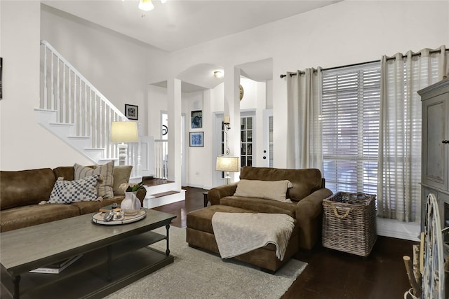 living area featuring stairs, arched walkways, dark wood-type flooring, and ceiling fan