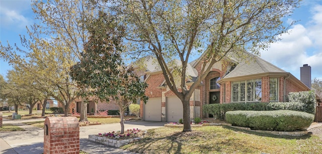 tudor house with brick siding, driveway, a shingled roof, and a garage