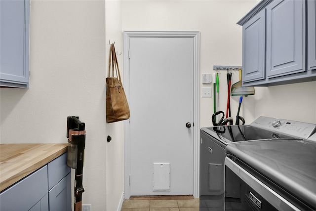 washroom with cabinet space, light tile patterned flooring, and washer and clothes dryer