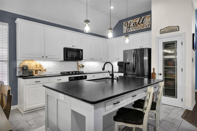 kitchen featuring stainless steel fridge with ice dispenser, dark countertops, a sink, black microwave, and decorative backsplash