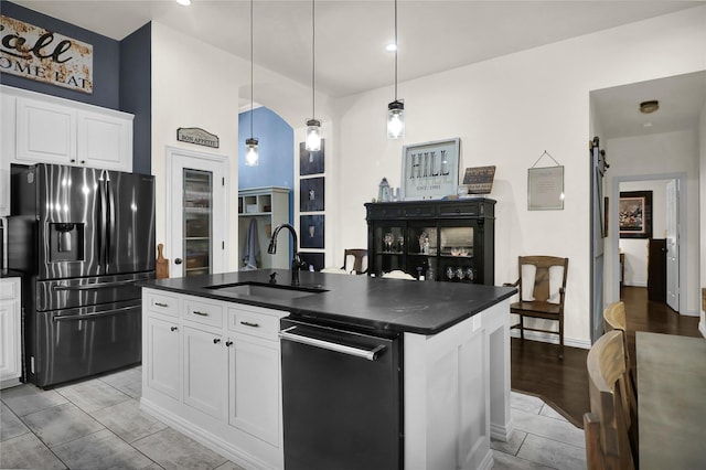 kitchen featuring dark countertops, stainless steel refrigerator with ice dispenser, an island with sink, and a sink