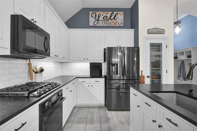 kitchen featuring dark countertops, a sink, white cabinetry, and black appliances