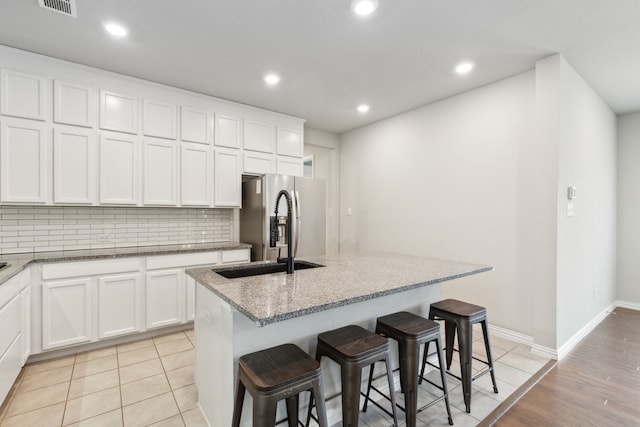 2549 Stella Ln, Northlake, TX 76247 - kitchen featuring stainless steel refrigerator with ice dispenser, tasteful backsplash, an island with sink, light stone countertops, and white cabinetry