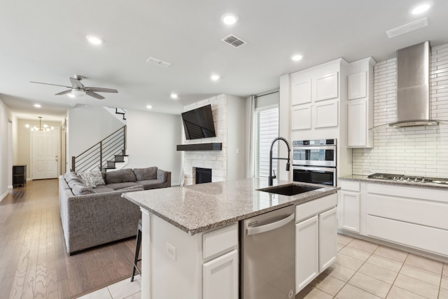 2549 Stella Ln, Northlake, TX 76247 - kitchen with wall chimney range hood, stainless steel appliances, a sink, a kitchen island with sink, and a fireplace