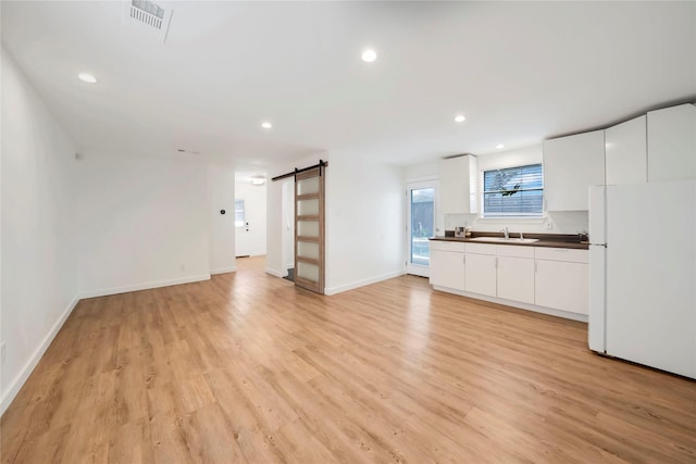 930 N Clinton Ave, Dallas, TX 75208 - unfurnished living room featuring a barn door, a sink, light wood-type flooring, recessed lighting, and baseboards