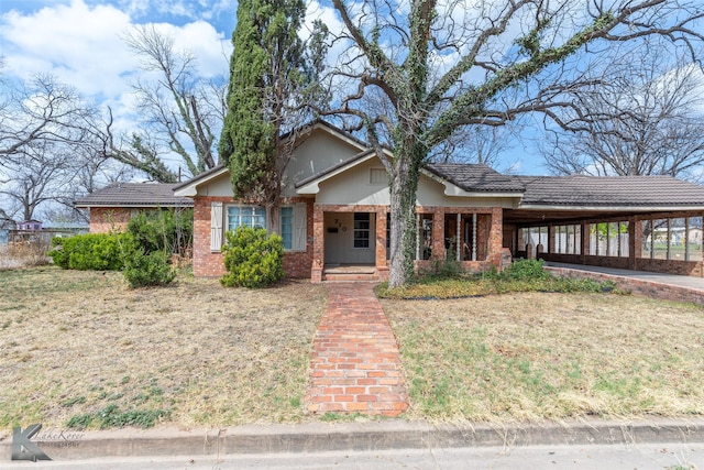 ranch-style house featuring driveway, brick siding, a front yard, and a carport