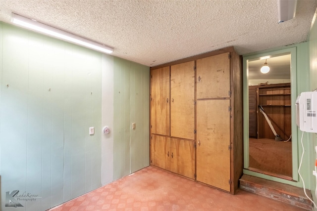 interior space with wooden walls, a closet, light floors, and a textured ceiling