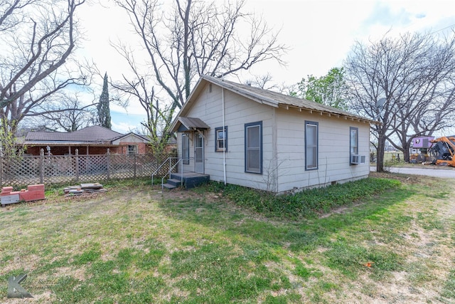 view of home's exterior featuring cooling unit, fence, and a lawn