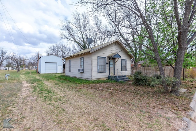 view of front facade with a detached garage, fence, and an outdoor structure