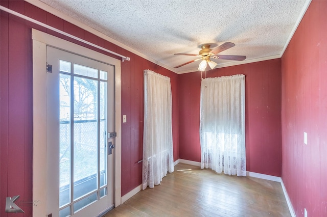 entrance foyer featuring a textured ceiling, ornamental molding, wood finished floors, and plenty of natural light