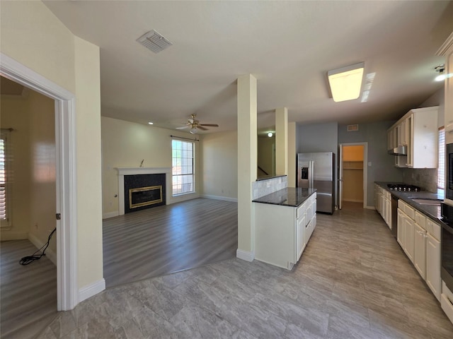 701 Canal St, Irving, TX 75063 - kitchen featuring appliances with stainless steel finishes, a ceiling fan, a glass covered fireplace, and baseboards
