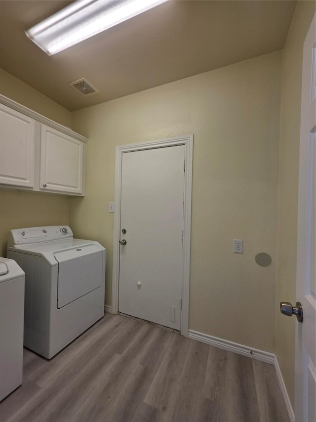 701 Canal St, Irving, TX 75063 - laundry area with cabinet space, light wood finished floors, washer and clothes dryer, and baseboards