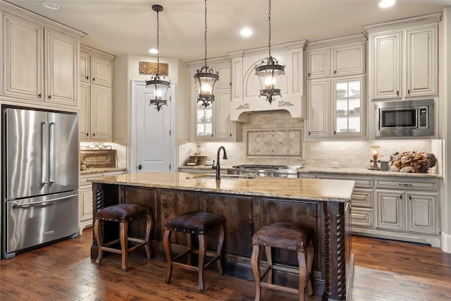 kitchen featuring cream cabinetry, a sink, appliances with stainless steel finishes, and a kitchen bar