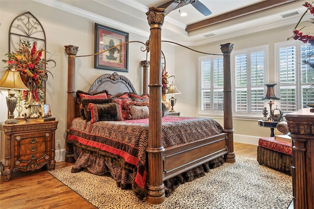 bedroom with wood finished floors, crown molding, and visible vents