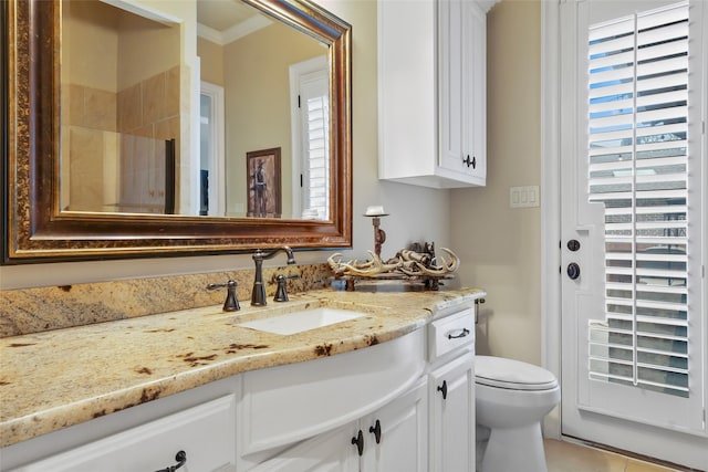 bathroom with toilet, ornamental molding, and vanity