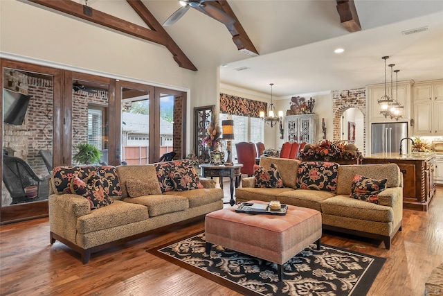 living room with beamed ceiling, visible vents, arched walkways, and light wood-type flooring