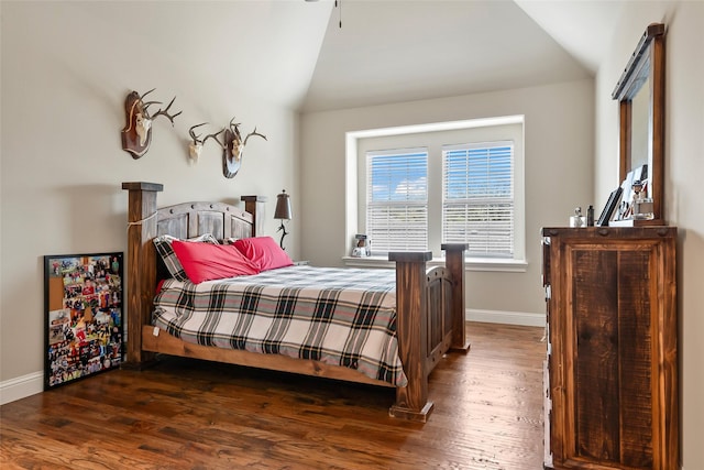 bedroom featuring baseboards, wood finished floors, and vaulted ceiling