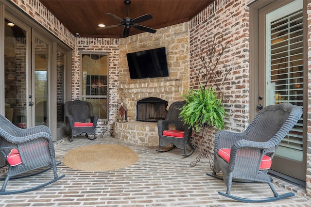 view of patio with an outdoor stone fireplace and ceiling fan