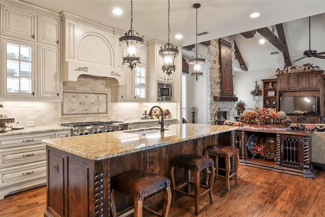 kitchen with light stone countertops, cream cabinetry, and a sink