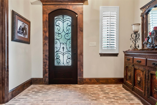 entryway featuring baseboards, brick floor, and arched walkways