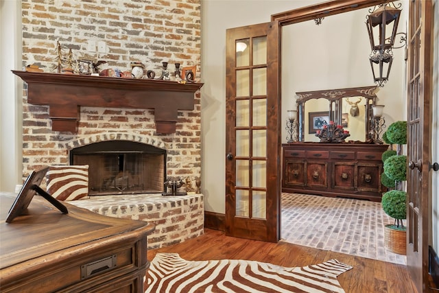 living area featuring a fireplace, wood finished floors, and french doors