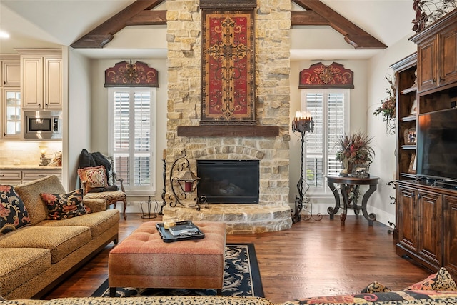 living area with baseboards, vaulted ceiling, wood finished floors, and a fireplace