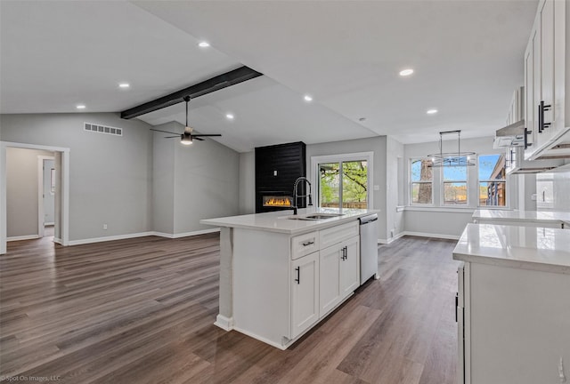 kitchen with a sink, visible vents, a brick fireplace, dishwasher, and vaulted ceiling with beams