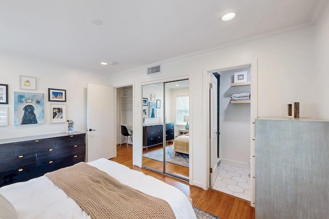 bedroom featuring a closet, ornamental molding, visible vents, recessed lighting, and light wood finished floors