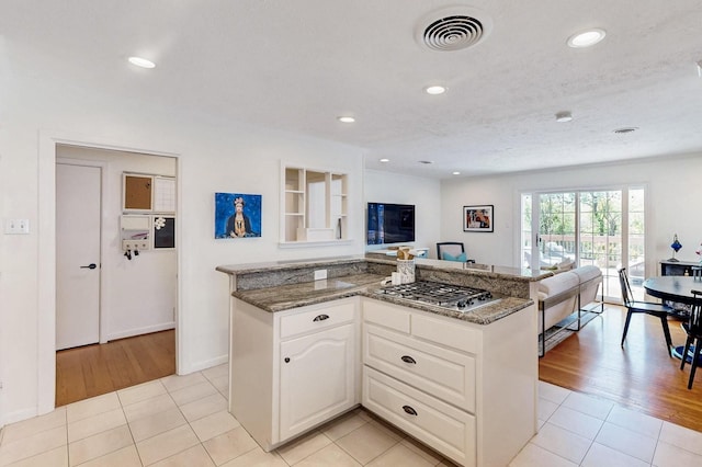 kitchen featuring dark stone counters, stainless steel gas stovetop, visible vents, and light tile patterned floors