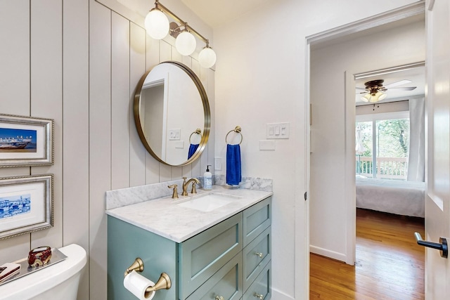 ensuite bathroom featuring wood finished floors, connected bathroom, vanity, and toilet