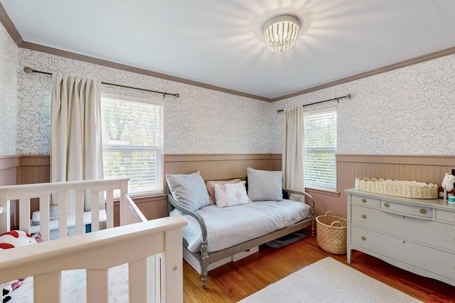 bedroom with wallpapered walls, crown molding, and wainscoting
