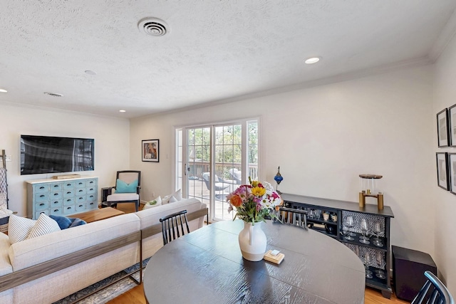 dining room with recessed lighting, wood finished floors, visible vents, crown molding, and a textured ceiling