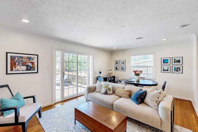 living area with light wood-type flooring, recessed lighting, plenty of natural light, and a textured ceiling