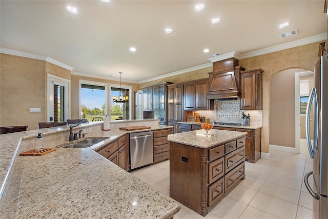 kitchen featuring appliances with stainless steel finishes, visible vents, a spacious island, arched walkways, and a sink