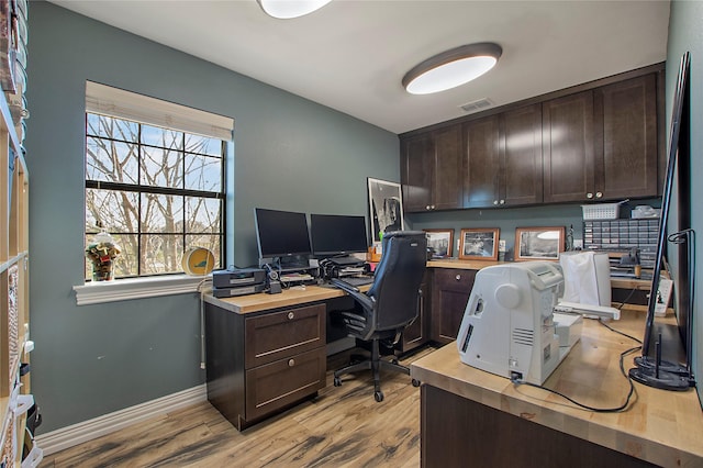home office with visible vents, light wood-type flooring, baseboards, and a healthy amount of sunlight