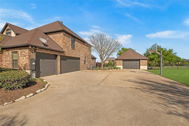 view of side of property with brick siding, roof with shingles, concrete driveway, and a lawn