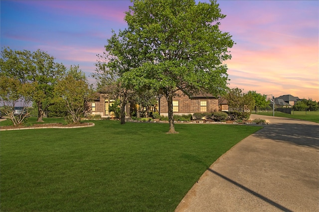 view of front of home with brick siding, driveway, and a lawn