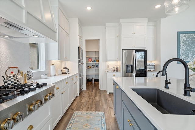 3340 Cabin Crest Pl, Frisco, TX 75033 - kitchen with stainless steel appliances, a sink, wall chimney exhaust hood, white cabinetry, and recessed lighting