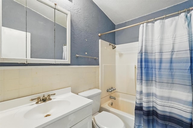 bathroom with a textured ceiling, tile walls, shower / tub combo, vanity, and a textured wall