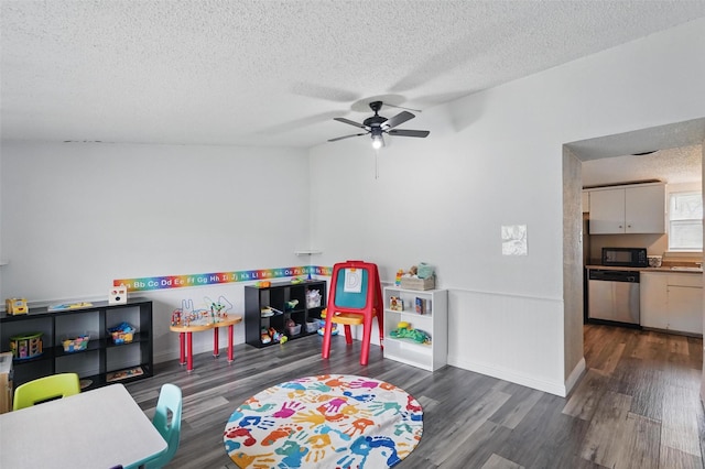 recreation room featuring baseboards, a textured ceiling, ceiling fan, and wood finished floors