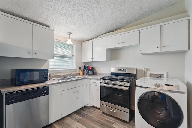 kitchen featuring a textured ceiling, washer / clothes dryer, appliances with stainless steel finishes, a sink, and white cabinets