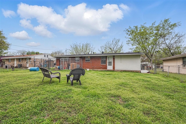 back of property featuring a lawn, fence, and brick siding