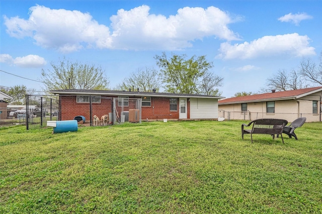back of property featuring a lawn, fence, and brick siding