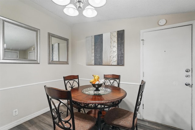 dining area featuring baseboards, a textured ceiling, dark wood-style flooring, and a chandelier