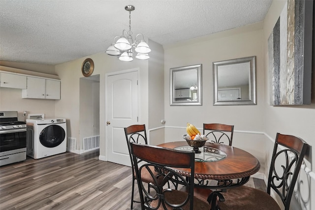 dining space with a notable chandelier, a textured ceiling, washer / clothes dryer, wood finished floors, and visible vents