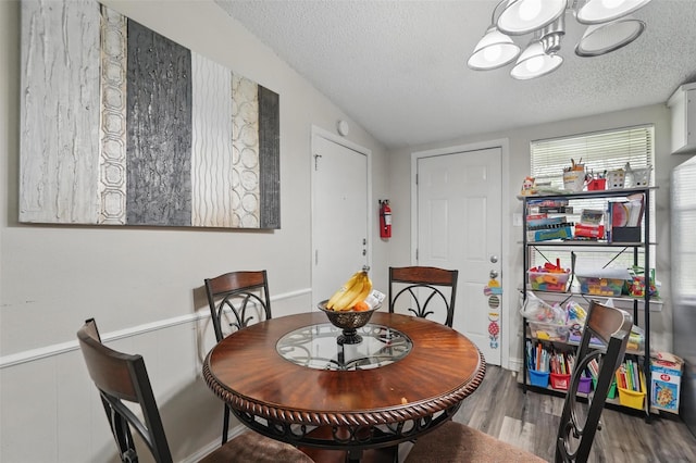 dining area with a textured ceiling, wood finished floors, and a notable chandelier