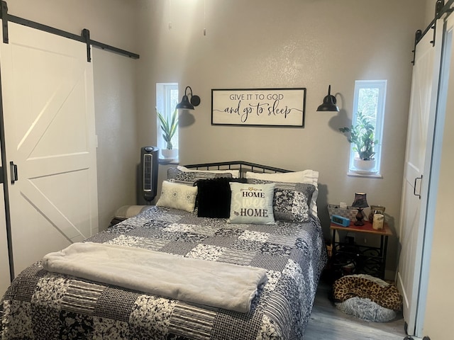 bedroom with multiple windows, a barn door, and wood finished floors