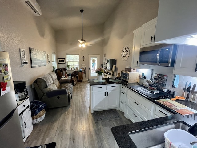 kitchen featuring a peninsula, wood finished floors, dark countertops, appliances with stainless steel finishes, and open floor plan