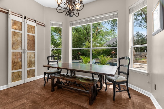 dining area featuring a chandelier, baseboards, and a barn door